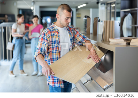 Male buyer carefully selects laminate flooring in hardware store 130314016