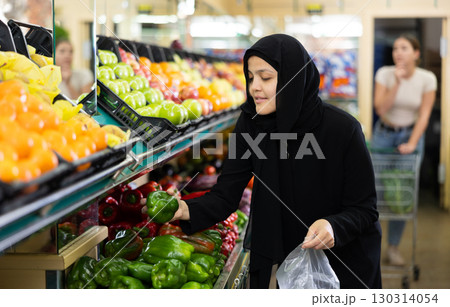 Young woman in hijab buys bell pepper at grocery store Young woman in hijab buys bell pepper at grocery store 130314054