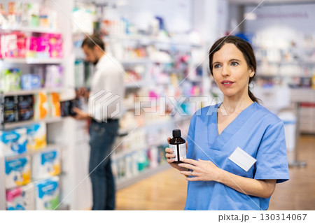 Female pharmacist offering product, working in drugstore Female pharmacist offering product, working in drugstore 130314067