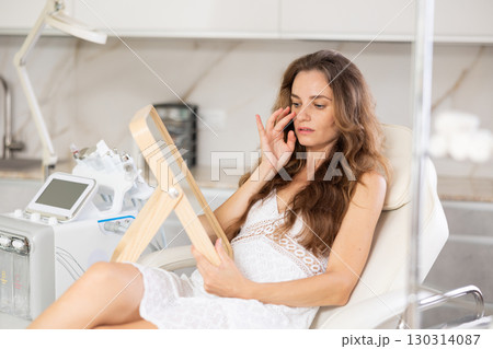 Young upset woman examining her face after cosmetic procedure Young upset woman examining her face after cosmetic procedure 130314087
