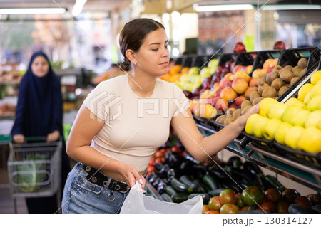 Young woman shopper chooses apples in supermarket Young woman shopper chooses apples in supermarket 130314127