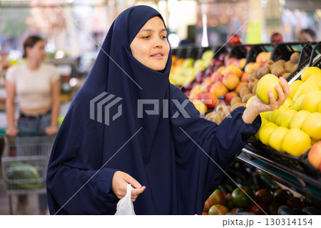 Young asian woman in hijab chooses quality juicy ripe apples 130314154