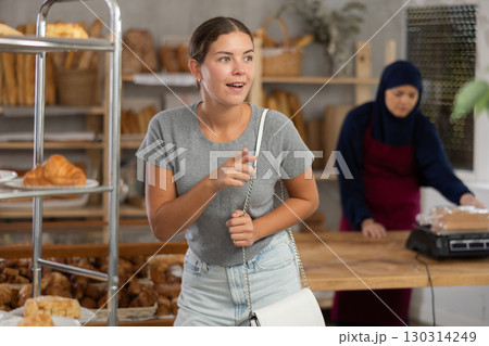 Girl choosing fresh pastries from display at Muslim bakery Girl choosing fresh pastries from display at Muslim bakery 130314249