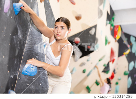 Woman training at bouldering gym without special climbing equipment Woman training at bouldering gym without special climbing equipment 130314289