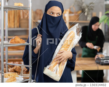 Muslim woman in niqab with baguettes in hands shopping at bakery Muslim woman in niqab with baguettes in hands shopping at bakery 130314402