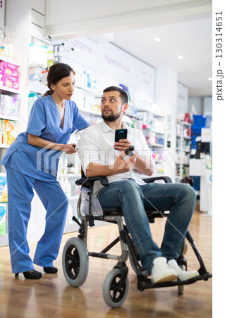 Female pharmacist advising disabled man in drugstore 130314651