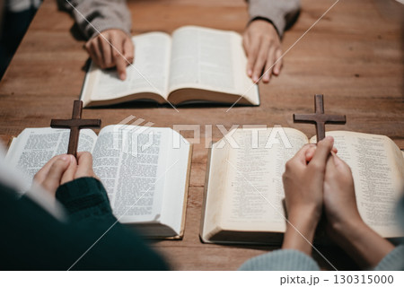 Group of Christians sit together and pray around a wooden table with blurred open Bible pages in their homeroom. Group of Christians sit together and pray around a wooden table with blurred open Bible pages in their homeroom. 130315000