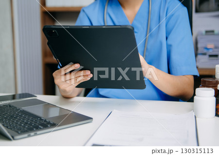 Professional nurse in blue scrubs using smartphone and laptop for medical data, prescription management, and digital healthcare solutions. Professional nurse in blue scrubs using smartphone and laptop for medical data, prescription management, and digital healthcare solutions. 130315113