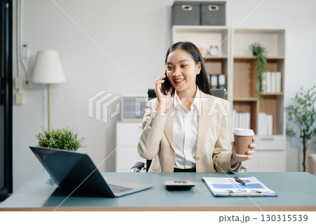Asian woman using laptop and tablet while sitting at her working place. Concentrated at work. Asian woman using laptop and tablet while sitting at her working place. Concentrated at work. 130315539