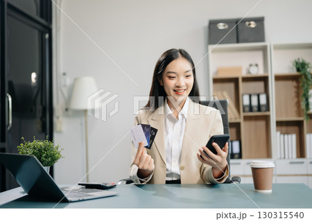Woman using smart phone for mobile payments online shopping, omni channel, sitting on table 130315540