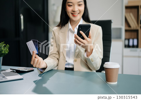 Woman using smart phone for mobile payments online shopping, omni channel, sitting on table Woman using smart phone for mobile payments online shopping, omni channel, sitting on table 130315543