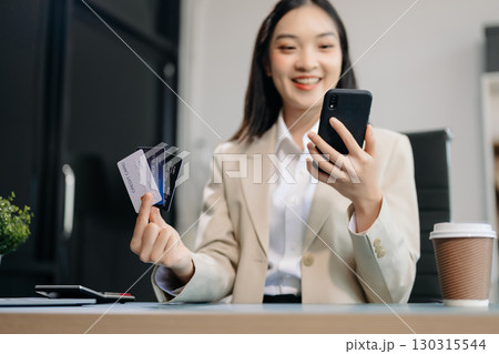 Woman using smart phone for mobile payments online shopping, omni channel, sitting on table Woman using smart phone for mobile payments online shopping, omni channel, sitting on table 130315544