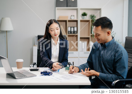 Asian people car salesman or sales manager offers to sell a car and explains of signing a car contract Asian people car salesman or sales manager offers to sell a car and explains of signing a car contract 130315585