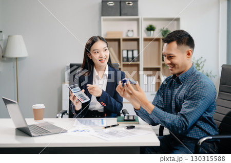 Asian people car salesman or sales manager offers to sell a car and explains of signing a car contract 130315588