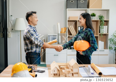 Construction team shake hands greeting start new project plan behind yellow helmet on desk in office center Construction team shake hands greeting start new project plan behind yellow helmet on desk in office center 130315652