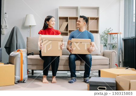 Young couple with big boxes moving into a new house, new apartment for couple, young asian man and woman helping to lift boxes on sofa 130315803