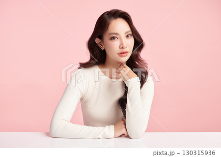 A beautiful young Asian woman with clean, fresh skin against a pink background. Skincare, facial treatment, cosmetology, beauty, and spa. An elegant portrait of an Asian woman. 130315936