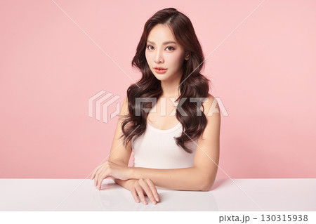 A beautiful young Asian woman with clean, fresh skin against a pink background. Skincare, facial treatment, cosmetology, beauty, and spa. An elegant portrait of an Asian woman. 130315938