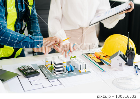 Two colleagues discussing data working and tablet, laptop with architectural project at construction site at desk Two colleagues discussing data working and tablet, laptop with architectural project at construction site at desk 130316332