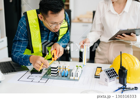 Two colleagues discussing data working and tablet, laptop with architectural project at construction site at desk Two colleagues discussing data working and tablet, laptop with architectural project at construction site at desk 130316333