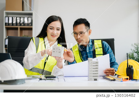 Creative architect projecting on the big drawings with architectural project at construction site at desk 130316402