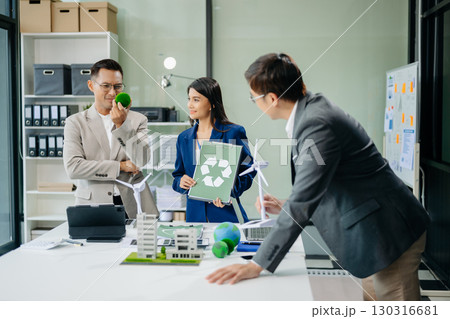 Group of businesspeople standing neare table looking at model of building from residential project. Green business company and Solar Energy 130316681