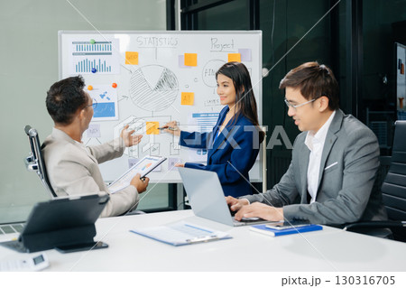 Office colleagues have a casual discussion. During a meeting in a conference room, a group of Asian business teem sit in the conference room 130316705
