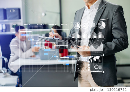 Businessman hand Project manager working and update tasks and Gantt chart scheduling virtual diagram.with smart phone, tablet Businessman hand Project manager working and update tasks and Gantt chart scheduling virtual diagram.with smart phone, tablet 130316732