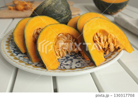 Pieces, slices of pumpkin on porcelain plate with blue pattern. Farm products and healthy eating. Kitchen and home cooking. Pieces, slices of pumpkin on porcelain plate with blue pattern. Farm products and healthy eating. Kitchen and home cooking. 130317708