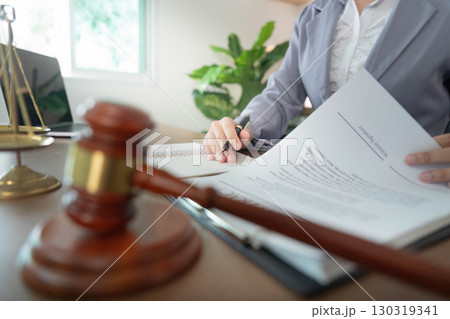 Legal Documentation. Businesswoman signing contract with gavel in foreground. Legal Documentation. Businesswoman signing contract with gavel in foreground. 130319341
