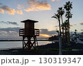 A wooden lifeguard tower stands silhouetted against the sky at sunset on a black sand beach in Lanzarote, Spain. 130319347