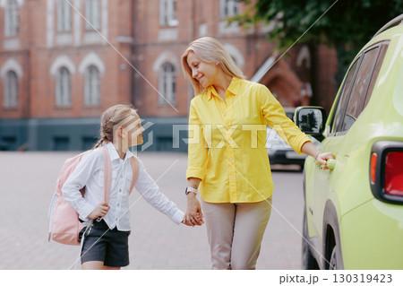 Mother and daughter holding hands walking to school in the morning showing support and love on the first day back. 130319423