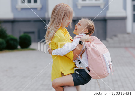 Happy mother hugs her daughter before school, family bonding and education, back to school, parent and child together. 130319431