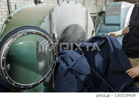 Industrial washing machine cleans textiles in modern factory, demonstrating large scale laundry and fabric care workflow 130319439