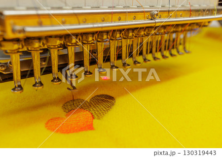 Automated embroidery machine creating colorful heart pattern on fabric, symbolizing love, creativity, and textile design process. Automated embroidery machine creating colorful heart pattern on fabric, symbolizing love, creativity, and textile design process. 130319443