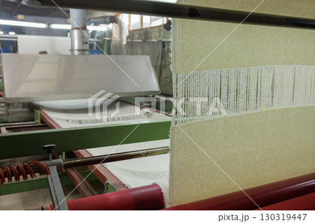 Wool fabric production line with weaving machine in textile factory, showing industrial process and threads for garment manufacturing. Wool fabric production line with weaving machine in textile factory, showing industrial process and threads for garment manufacturing. 130319447