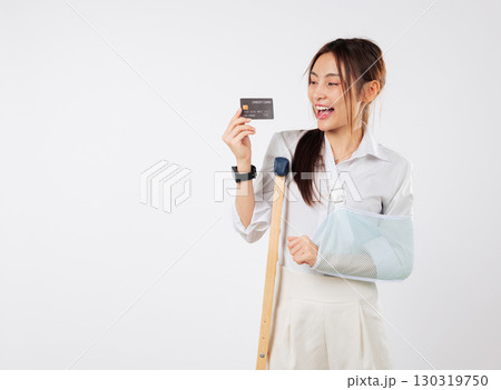 Happy injured Asian woman with broken leg arm using credit card, paying insurance for accident healthcare with plaster cast and sling support, smiles after buying insurance, isolated white background Happy injured Asian woman with broken leg arm using credit card, paying insurance for accident healthcare with plaster cast and sling support, smiles after buying insurance, isolated white background 130319750