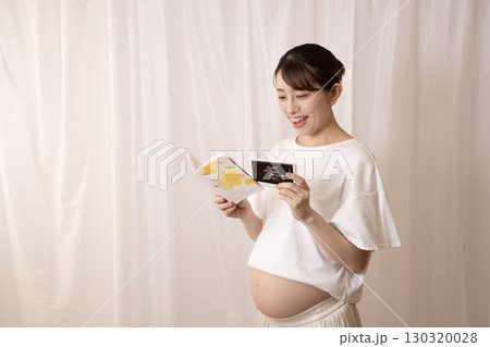 母子手帳とエコー写真を見る妊婦の女性 130320028
