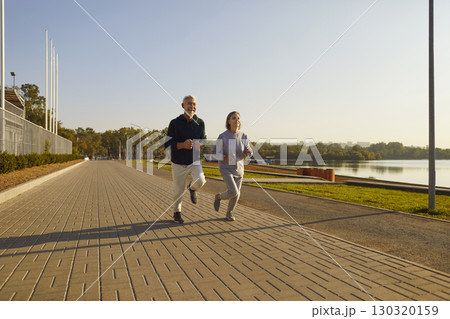 Happy senior family couple having jogging workout and running on city waterfront Happy senior family couple having jogging workout and running on city waterfront 130320159