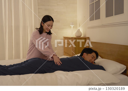 ベッドの上で夫をマッサージする妻 130320189