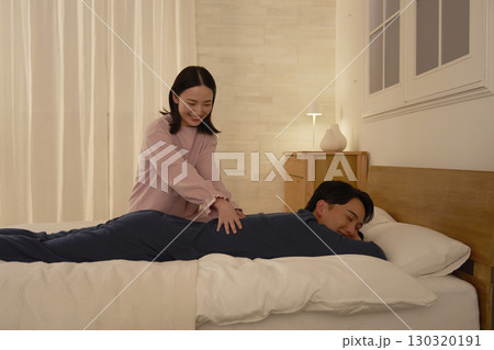 ベッドの上で夫をマッサージする妻 130320191