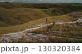Tourist walking along a scenic path in the Sumba hills of Indonesia, soaking in the breathtaking landscape on a sunny day while enjoying a refreshing hike through the wilderness 130320384