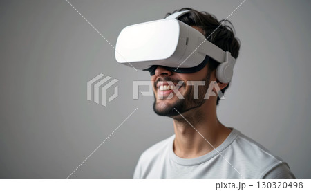 Man Smiling While Wearing a Virtual Reality Headset in a White Environment. 130320498