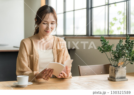 カフェでコーヒーを飲みながら読書をする女性 130321589