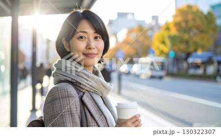 日本人女性の肩上ポートレート バス停で朝のコーヒーを持つ 130322307