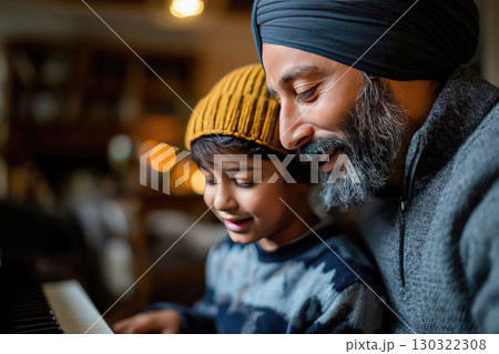 Side-view of a mid adult father teaching his real young son how to play the piano. The father and son are Sikh, and they are both wearing turbans with casual clothing 130322308
