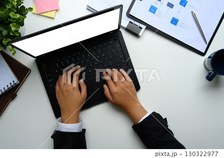 Overhead shot of businesswoman working on laptop with documents on desk Overhead shot of businesswoman working on laptop with documents on desk 130322977