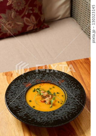 Indulge in Gourmet Pumpkin Soup presented in an Elegant Black Bowl, perfect for dining 130323145