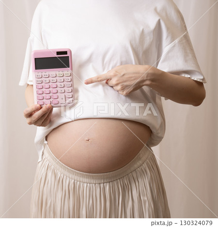 ピンクの電卓を持つ妊婦さん ピンクの電卓を持つ妊婦さん 130324079