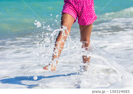 Child playing in sea foam at the beach 130324085